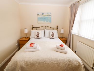 A bedroom with a double bed with rabbit pillows and bedside tables with lamps at 14 The Maltings in Rothbury