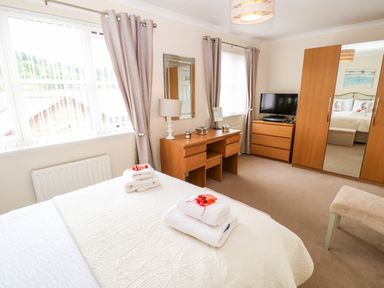 A bedroom with a bed with folded towels a wooden dresser and wardrobe with mirrored doors at 14 The Maltings in Rothbury