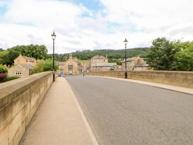 A road bridge with street lamps and stone buildings in the background at 14 The Maltings in Rothbury