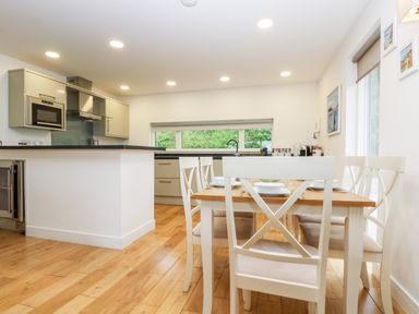 A kitchen and dining area with a wooden table and white chairs at Beech in Truro