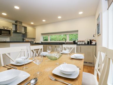 A dining table set with plates bowls glasses and cutlery in a kitchen with cabinets and appliances at Beech in Truro