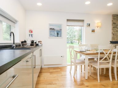 A kitchen with a sink and countertop next to a dining table with chairs and tableware at Beech in Truro