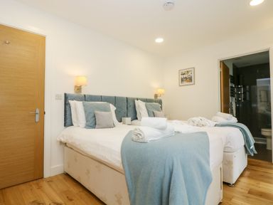 A bedroom with two single beds dressed with white sheets and blue cushions and blankets at Beech in Truro