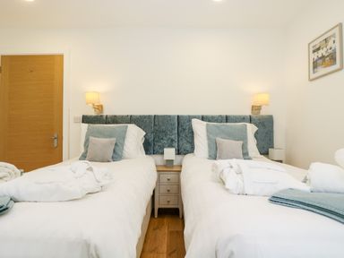 A bedroom with two single beds with pillows and blankets a wooden door and a bedside table at Beech in Truro