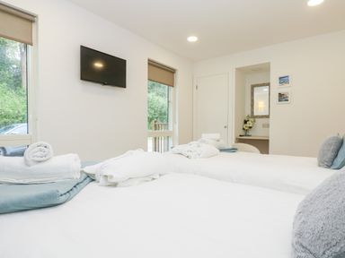 A bedroom with two beds a wall-mounted television and a small desk with a mirror at Beech in Truro