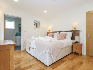 A bedroom with a double bed pillows and rolled towels beside a wooden nightstand and an open door to a bathroom at Beech in Truro