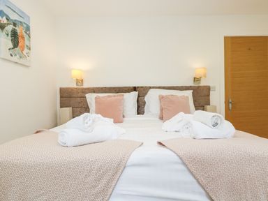 A bedroom with a double bed two cushions two wall lamps and towels on the bed at Beech in Truro