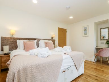 A bedroom with two beds side by side with bedding and pillows wooden floor and a desk with a chair and a mirror at Beech in Truro