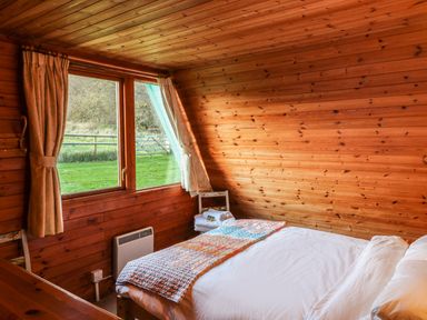 A bedroom with a bed near a window showing green grass outside at Rose Lodge in Milton on Stour
