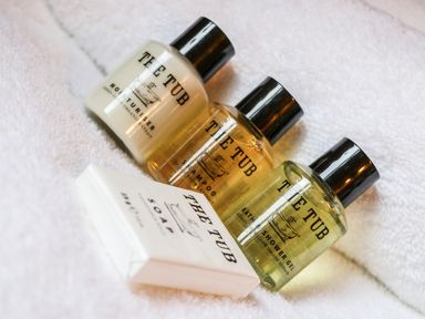 Three small toiletry bottles and a soap bar on a white towel at Rose Lodge in Milton on Stour