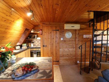 A wooden kitchen with a tiled countertop and a spiral staircase at Rose Lodge in Milton on Stour