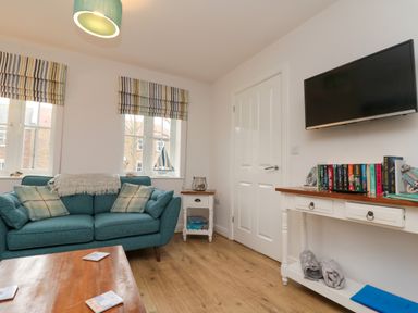 A living room with a teal sofa and a wooden coffee table with coasters at Dotty's Sunshine Cottage in The Bay near Filey