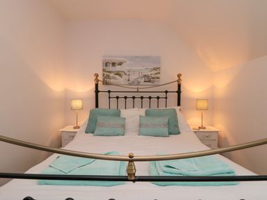 A bedroom with a metal bed frame two bedside tables with lamps and cushions on the bed at Dotty's Sunshine Cottage The Bay near Filey