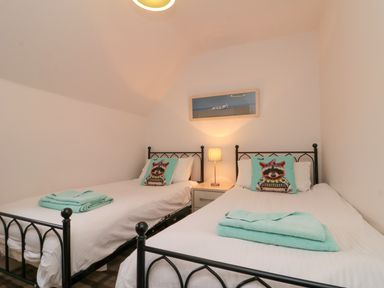 A bedroom with two single beds with animal print cushions and folded towels on each bed at Dotty's Sunshine Cottage in The Bay near Filey