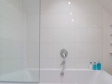 A bathtub with a wall-mounted faucet and three bottles on the edge at Dotty's Sunshine Cottage in The Bay near Filey