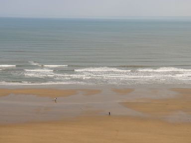 A sandy beach with two people and the sea at Dotty's Sunshine Cottage The Bay near Filey