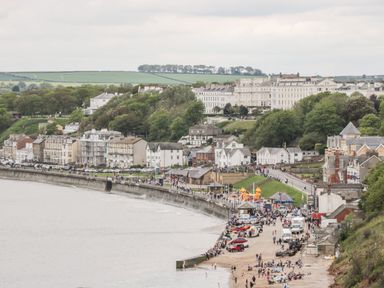 A coastal town with people on a beach and a promenade lined with houses and trees at Dotty's Sunshine Cottage The Bay near Filey