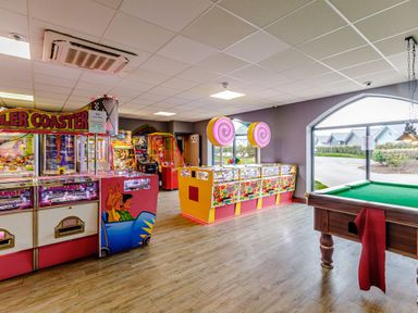 An arcade room with various gaming machines and a pool table near a large window at Dotty's Sunshine Cottage The Bay near Filey