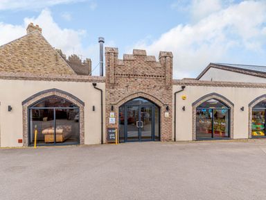 A brick building with arched windows and a double-door entrance with a sign reading the shop open 8 to 6