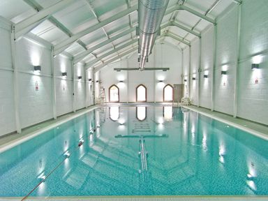 An indoor swimming pool with tiled floor and white walls at Dotty's Sunshine Cottage The Bay near Filey