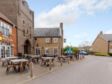 An outdoor seating area with tables and chairs near brick buildings at Dottys Sunshine Cottage The Bay near Filey
