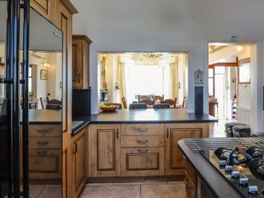 A kitchen with cabinets and a dining area at Wavecrest in Pwllheli