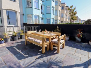 An outdoor dining area with a wooden table and chairs at Wavecrest in Pwllheli