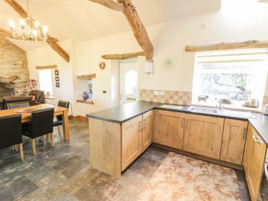 A kitchen and dining area with wooden beams on the ceiling at Yr Hen Dy in Llan Ffestiniog