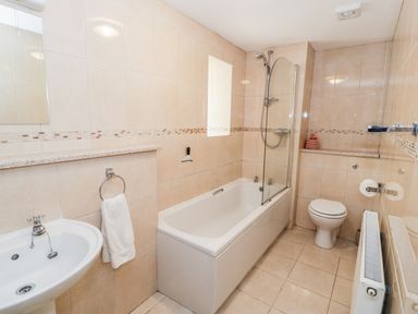A bathroom with a bathtub shower combination sink toilet and radiator at Yr Hen Dy in Llan Ffestiniog