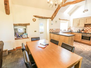 A kitchen with wooden cabinets and a dining table with black chairs at Yr Hen Dy in Llan Ffestiniog