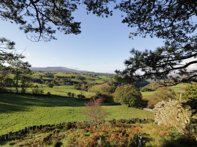 A countryside landscape with green fields trees and hills under a clear sky at Yr Hen Dy in Llan Ffestiniog