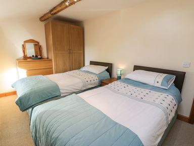 A bedroom with two single beds a wooden wardrobe a wooden chest of drawers and a bedside table with a lamp at Yr Hen Dy in Llan Ffestiniog