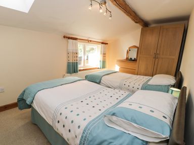 A bedroom with two single beds a wooden wardrobe a chest of drawers and curtains on a window at Yr Hen Dy in Llan Ffestiniog