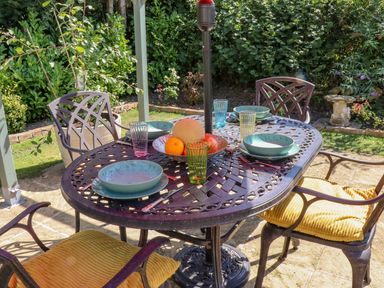 An outdoor dining table with four chairs and place settings in a garden at The Flat At Brwyn in Brynford