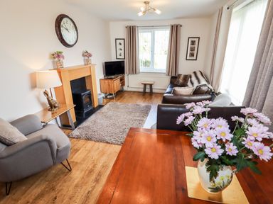 A living room with a sofa armchair fireplace television and flowers on a table at The Flat At Brwyn in Brynford