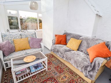 A sitting area with two sofas a glass coffee table and a patterned rug at The Flat At Brwyn in Brynford