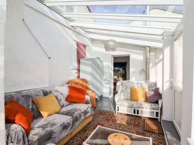 A sunroom with two sofas a glass coffee table and a patterned rug at The Flat At Brwyn in Brynford