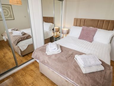A bedroom with a bed with folded towels on it next to a mirrored closet at The Flat At Brwyn in Brynford