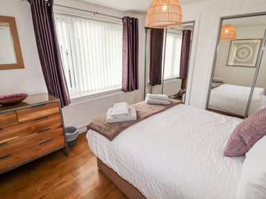 A bedroom with a bed folded towels wooden dresser and mirrored closet doors at The Flat At Brwyn in Brynford