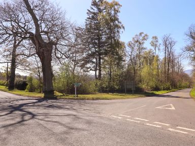 A road junction surrounded by trees and grass at Gamekeepers Cottage Chillingham near Chatton