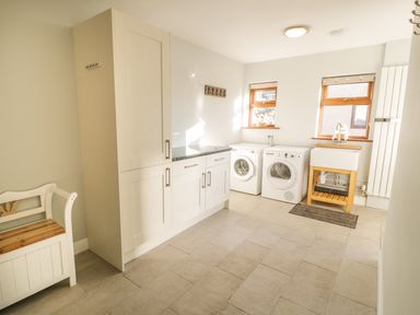 A laundry room with washing machine dryer sink cabinets and a bench at Awel Y Llan in Llanfair