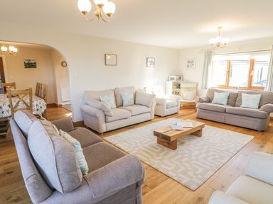 A living room with sofas a wooden coffee table and a dining area at Awel Y Llan in Llanfair
