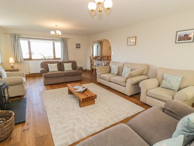 A living room with sofas coffee table and a dining area visible through an archway at Awel Y Llan in Llanfair