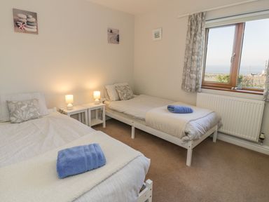 A bedroom with two single beds bedside tables with lamps and a window showing a view at Awel Y Llan in Llanfair