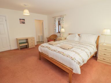 A bedroom with a double bed two bedside tables with lamps a desk and a chair at Awel Y Llan in Llanfair
