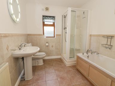A bathroom with a pedestal sink toilet shower enclosure and bathtub at Awel Y Llan in Llanfair