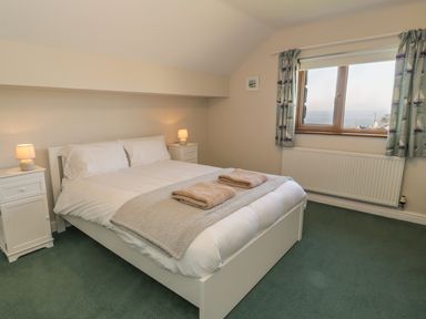 A bedroom with a double bed two bedside tables with lamps a window with curtains and a radiator at Awel Y Llan in Llanfair