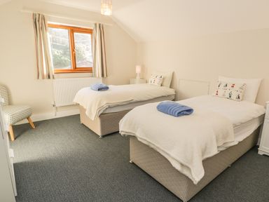 A bedroom with two single beds with white bedding and blue towels on each bed at Awel Y Llan in Llanfair