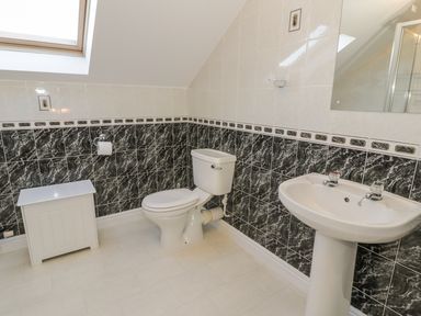 A bathroom with a toilet sink and a small cabinet under a skylight at Awel Y Llan in Llanfair