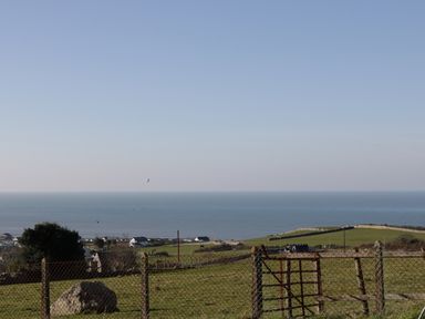 A rural landscape with grass fields and a fence overlooking the sea at Awel Y Llan in Llanfair